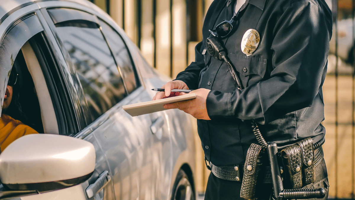 A police officer writing a ticket outside of a car